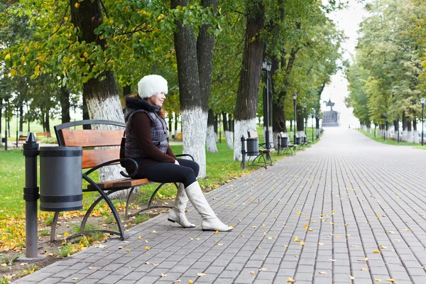 年轻漂亮的女人独自坐在公园的长椅上 — 图库照片