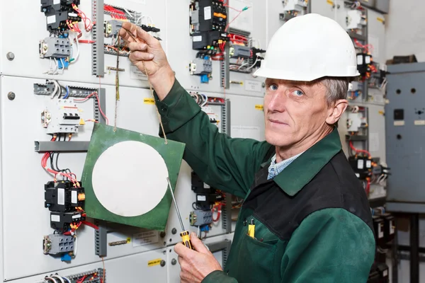 Electricista maduro trabajando en sombrero blanco duro con tablero de precaución —  Fotos de Stock