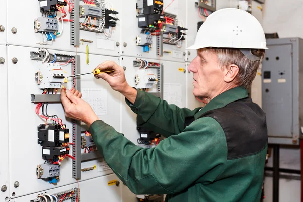 Eletricista maduro trabalhando em chapéu duro branco com cabos e fios . — Fotografia de Stock
