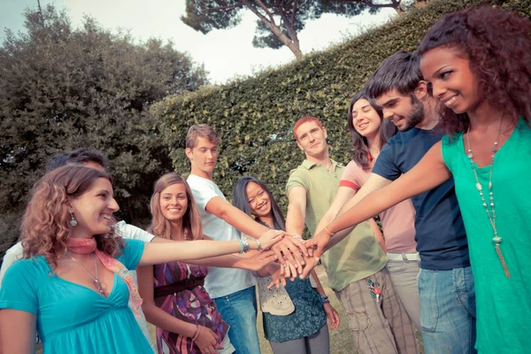Grupo adolescente feliz com as mãos na pilha — Fotografia de Stock