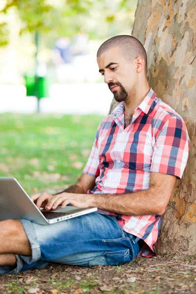Giovane uomo con computer a parco — Foto Stock
