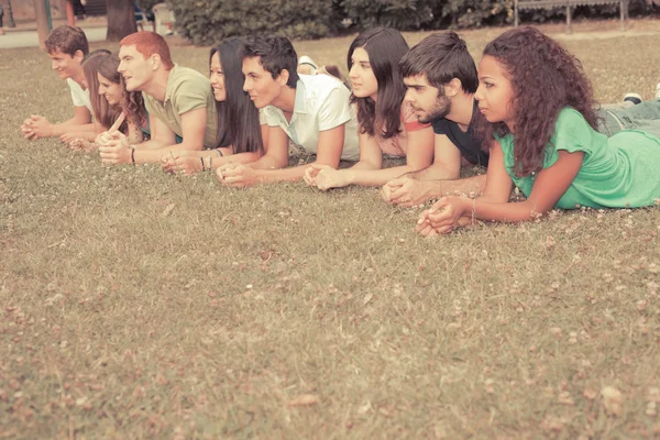Skupina teenagerů, ležící na zemi v parku — Stock fotografie