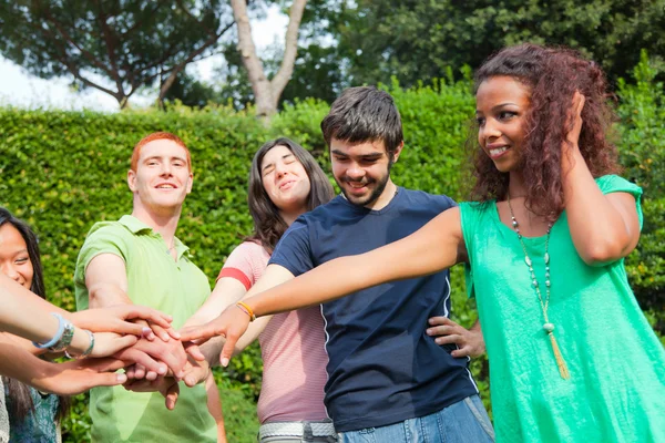 Grupo adolescente feliz com as mãos na pilha — Fotografia de Stock