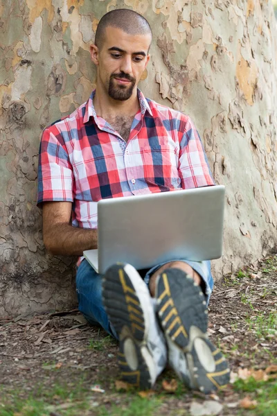 Giovane uomo con computer a parco — Foto Stock