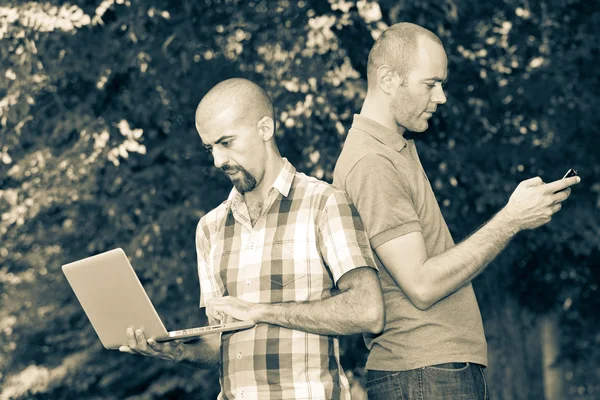 Due uomini con computer e telefono cellulare — Foto Stock