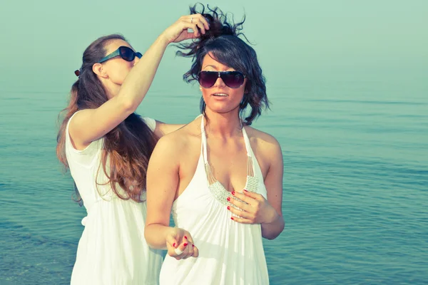 Ung kvinna klä sin vän hårstrån på seaside — Stockfoto