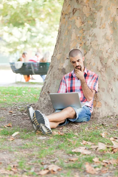 Junger Mann mit Computer im Park — Stockfoto