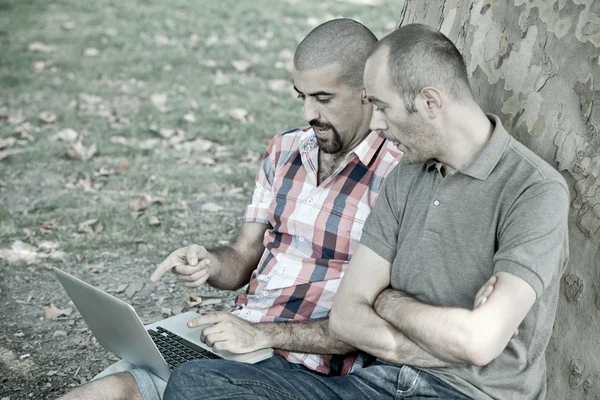 Deux hommes travaillant avec l'ordinateur au parc — Photo