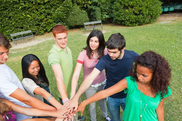 Buon gruppo di adolescenti con le mani sulla pila — Foto Stock