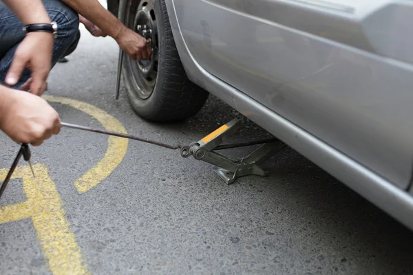 Adam bir jack arabasını kaldırmak için kullanılan — Stok fotoğraf