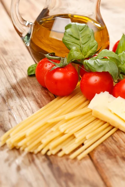Pasta's, olijfolie en tomaten op het hout achtergrond — Stockfoto
