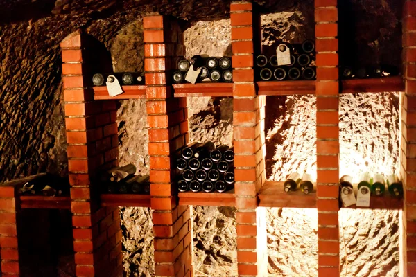 Garrafas de vinho em fileiras na adega — Fotografia de Stock