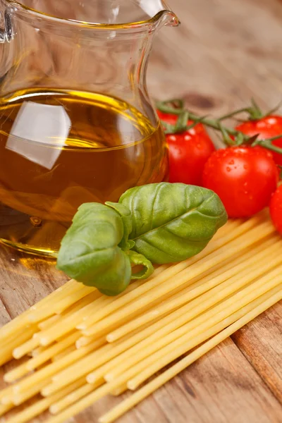 Макароны, оливковое масло и помидоры на деревянном фоне — стоковое фото
