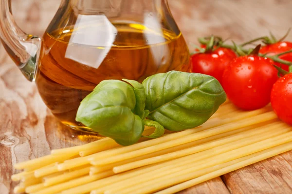 Pasta, olive oil and tomatoes on the wood background — Stock Photo, Image