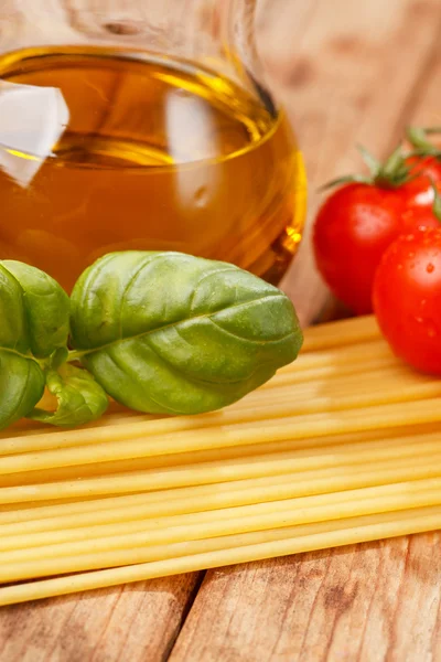 Makarna, zeytinyağı ve ahşap arka plan domates — Stok fotoğraf