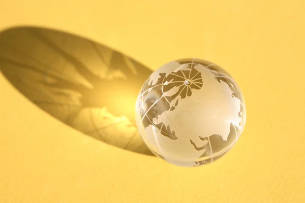 Стеклянный глобус на желтом — стоковое фото