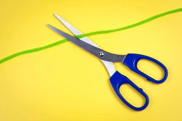Nůžky řez lano na žlutém podkladu. — Stock fotografie