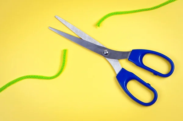Tesoura cortar corda em um fundo amarelo . — Fotografia de Stock