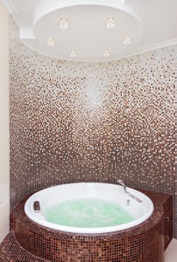 White round jacuzzi in modern bathroom with brown mosaic and cou clipart