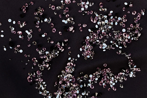 Diamante (pequeña joya púrpura) piedras amontonadas sobre tela de seda negro b —  Fotos de Stock