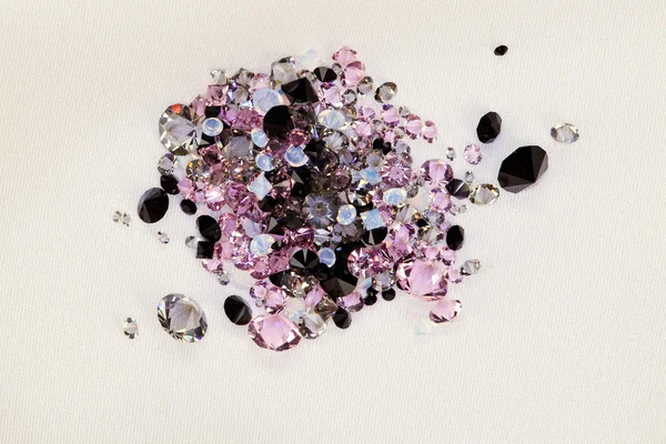 Lilla lila pärla stenar heap över grädde siden tyg bakgrund — Stockfoto
