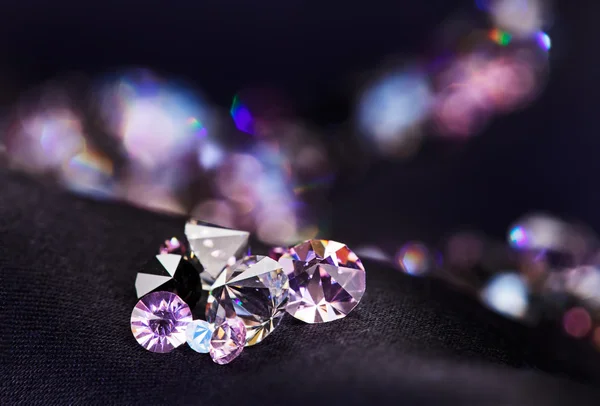 Diamond (small purple jewel) stones heap over black silk cloth b — Stock Photo, Image