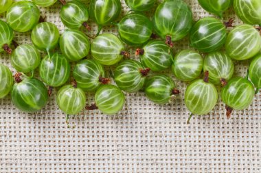 Many gooseberry fruits on gray linen table cloth with copy space