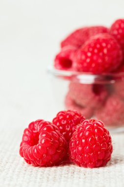 Still life with red raspberry and glass bowl on gray linen table clipart