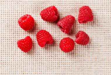 Many red ripe raspberry fruit, on gray linen table cloth with co clipart