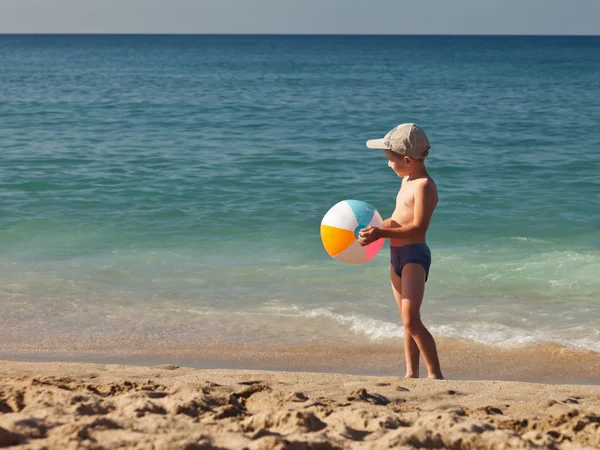 Child boy holding ball on sea sand beach — Stock Photo, Image