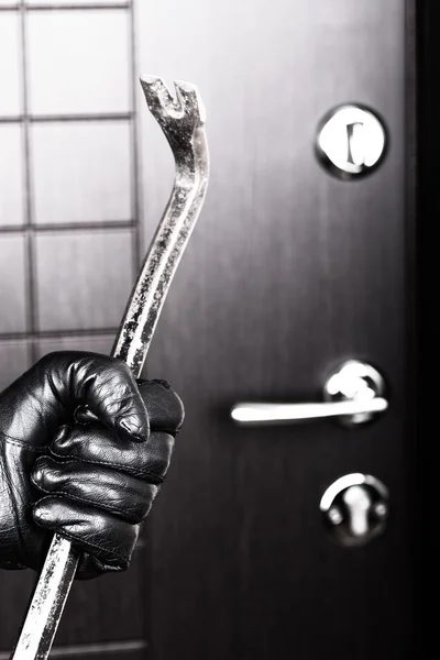 Рука грабителя держит ломик, открывая дверь — стоковое фото