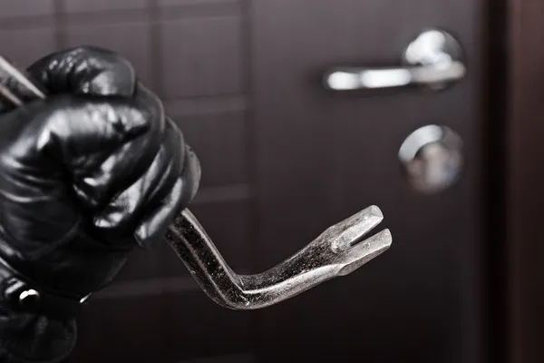 Burglar hand holding crowbar break opening door — Stock Photo, Image