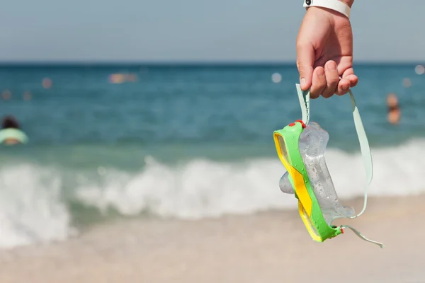 Hand met duiken bril op zee strand — Stockfoto