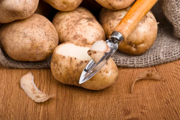 Frische Kartoffeln werden mit einem Küchenmesser geschält — Stockfoto