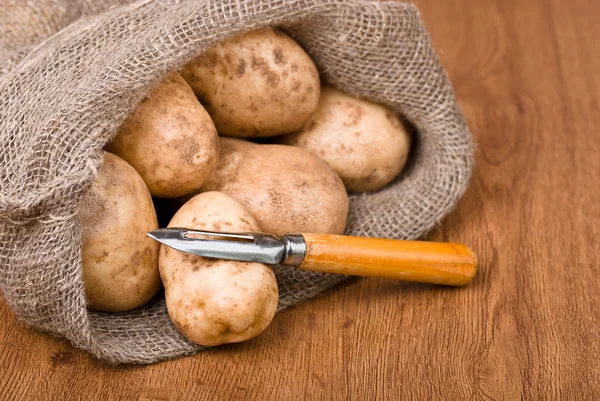 Πατάτες με μαχαίρι για να καθαρίσετε τα λαχανικά για το φυσικό backg — Φωτογραφία Αρχείου