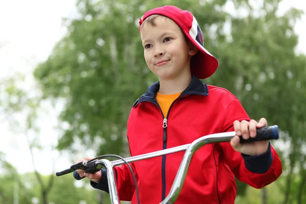 Jongen op een fiets in het groene park — Stockfoto