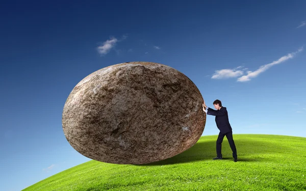 Бізнесмен катається на гігантському камені — стокове фото