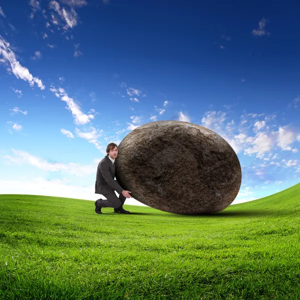 Uomo d'affari rotolando una pietra gigante — Foto Stock