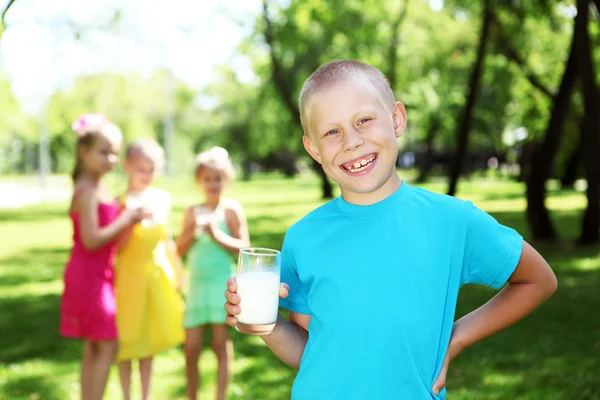 Мальчик пьет молоко в летнем парке — стоковое фото