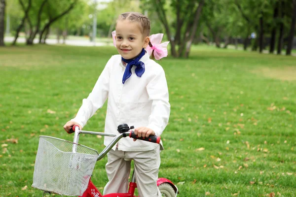 Menina em uma bicicleta no parque verde — Fotografia de Stock