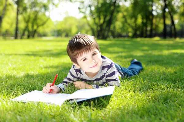 Podobizna chlapce s knihou v parku — Stock fotografie