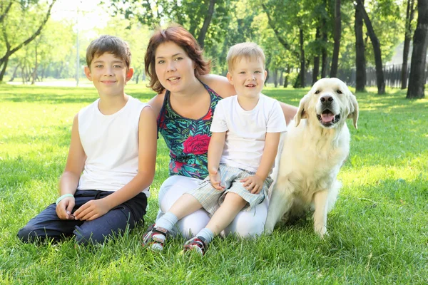 Мать с двумя сыновьями в парке с собакой — стоковое фото