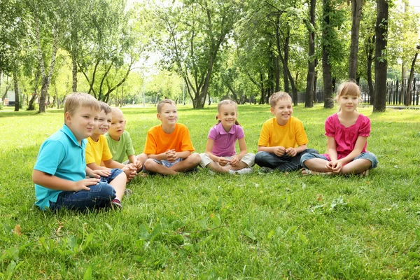 Csoport a gyermekek együtt ül a parkban — Stock Fotó