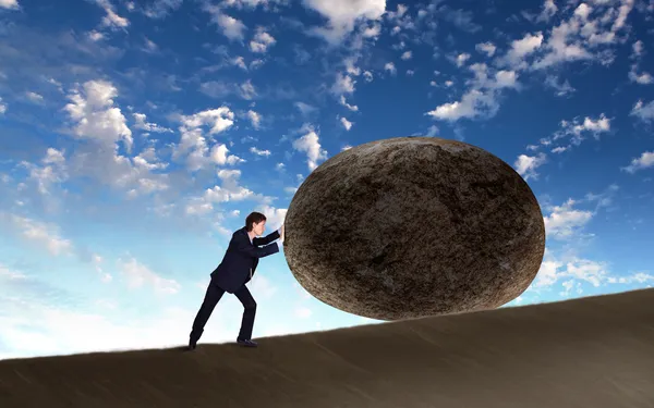 Businessman rolling a giant stone — Stock Photo, Image