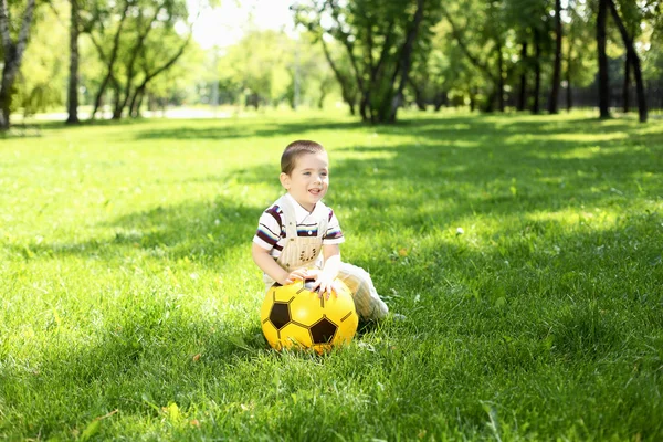 Kisfiú a parkban játszik a labdát sz — Stock Fotó