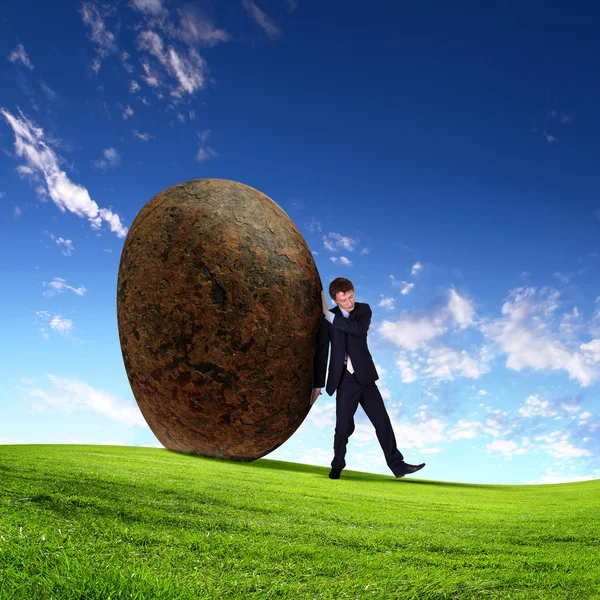 Бізнесмен катається на гігантському камені — стокове фото