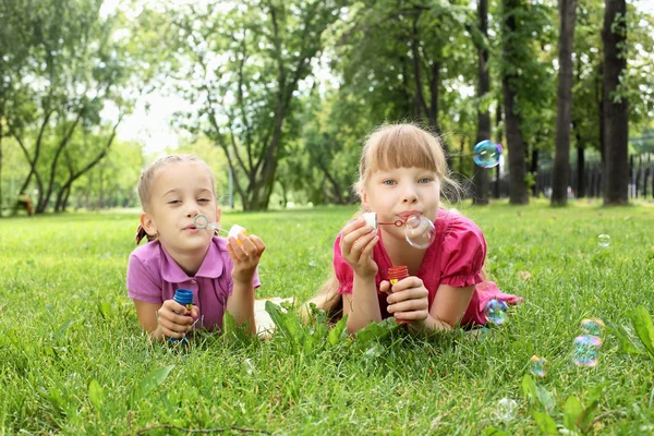 Menina no parque soprando bolhas — Fotografia de Stock