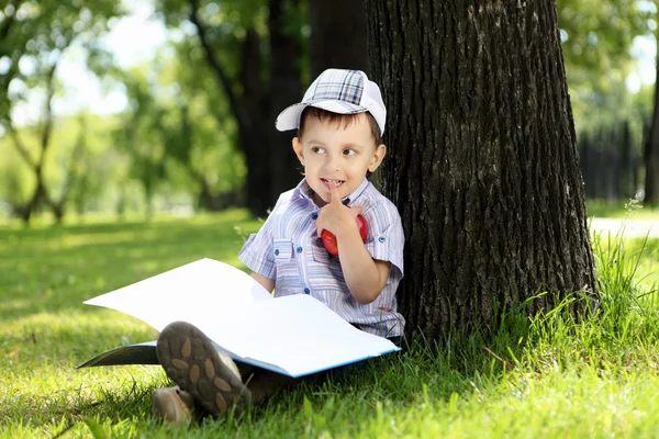 Retrato de un niño con un libro en el parque —  Fotos de Stock