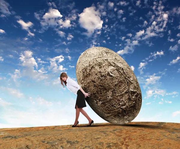 Бизнесвумен катит гигантский камень — стоковое фото