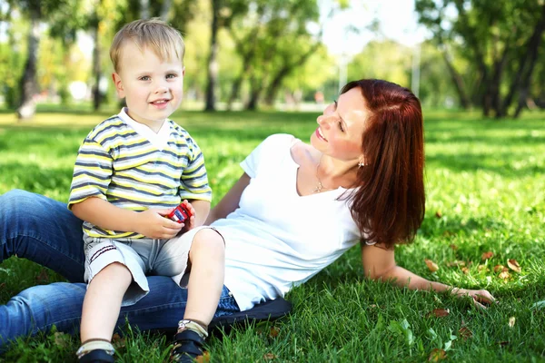 Młoda matka z synem w lato park — Zdjęcie stockowe